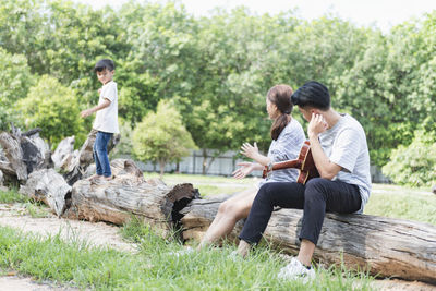 Side view of couple sitting on field