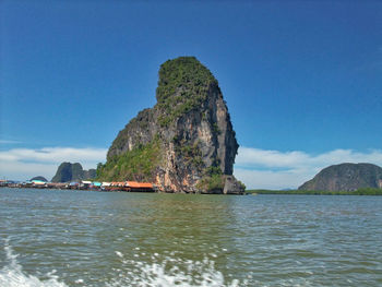 Rock formations in sea against blue sky