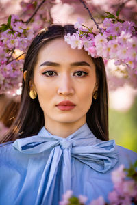 Portrait of woman by pink flowers on tree