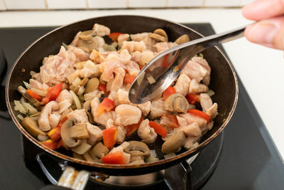 Close-up of hand holding meat in cooking pan