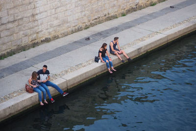 People sitting on bridge over river