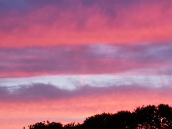 Low angle view of silhouette trees against dramatic sky