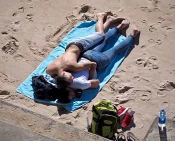 High angle view of friends relaxing on sand at beach