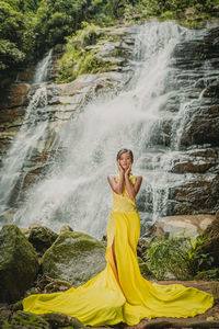 Full length of young woman in waterfall