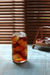 Close up of ice tea drink on the blue table and bamboo window at the background.
