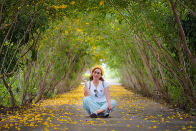 Side view of woman sitting on field in forest