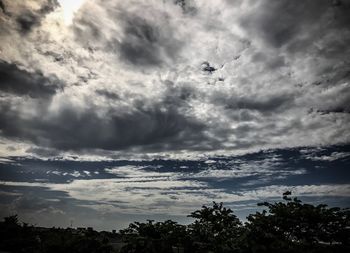 Low angle view of silhouette airplane flying against sky