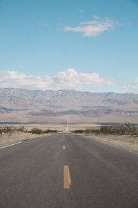 Road by desert against sky