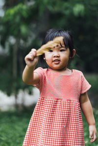 Cute girl holding feather while standing on field