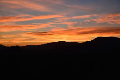 Scenic view of silhouette mountains against orange sky