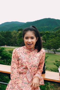 Portrait of smiling woman leaning on railing