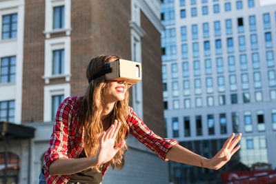 Woman wearing virtual reality headset while standing outdoors