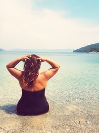 Rear view of overweight woman looking at sea against sky