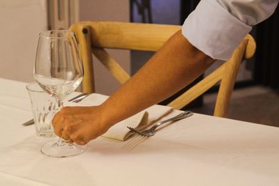 Midsection of person with drink on table