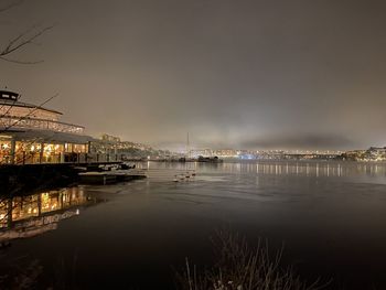 Illuminated bridge over river against sky at night