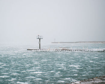 Lighthouse by sea against clear sky