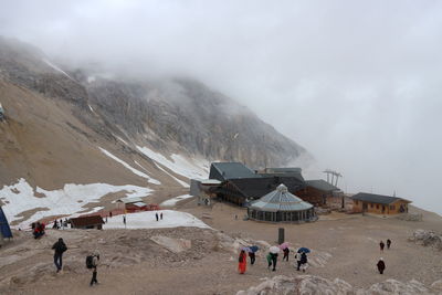 People on snowcapped mountains against sky