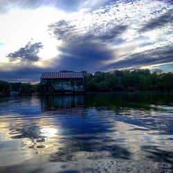 Scenic view of lake against cloudy sky at sunset