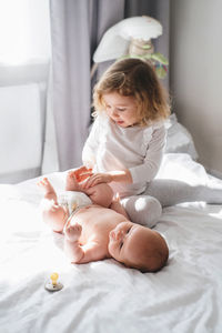 Older sister and baby brother play and the bed. two cute little children siblings playing at home