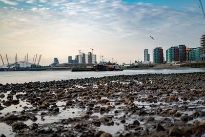 View of buildings at waterfront against cloudy sky