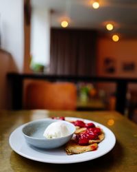 Pancakes with strawberries and ice cream in plate on table