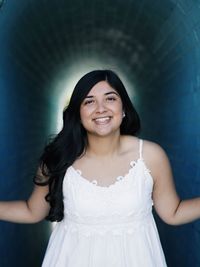 Portrait of smiling young woman standing against white background