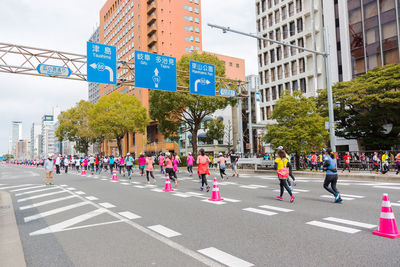 Group of people walking on road along buildings