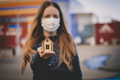 Portrait of young woman standing against building