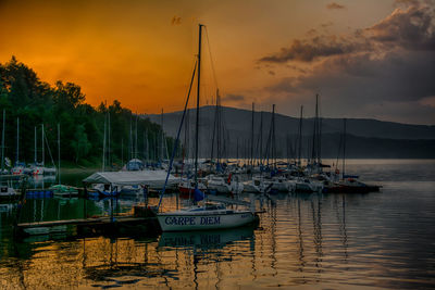 Boats moored at harbor during sunset