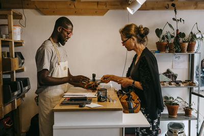 Senior customer making online payment to male owner in bicycle shop