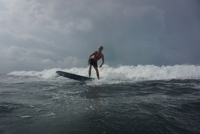 Full length of man surfing in sea against sky