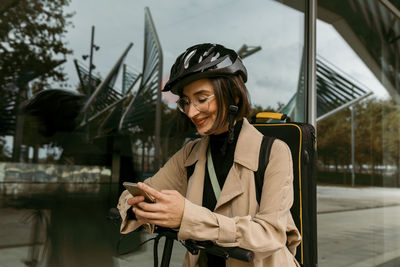 Young woman using smart phone while standing outdoors