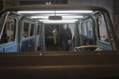 Engineer examining van in automobile factory seen through windshield