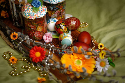 High angle view of easter eggs with flowers and sweet food on textile