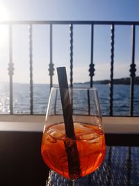 Close-up of drink in glass on table by sea 