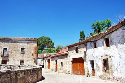 Alley by lane against clear blue sky