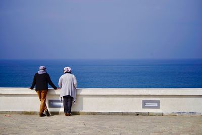 Rear view of people looking at sea against clear sky