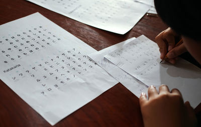 Midsection of boy writing on paper at home