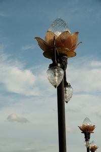 Low angle view of sculpture on pole against sky