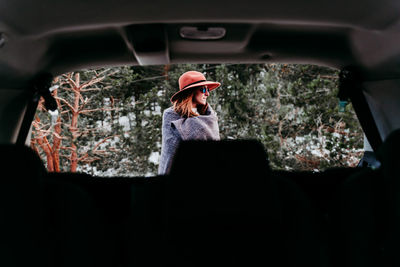 Woman wearing hat seen through car outdoors