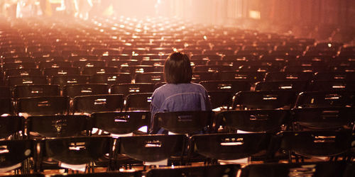 Rear view of woman sitting in empty theater