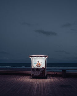 Rear view of man sitting in sea against sky