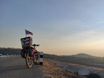 Bicycle on road against sky during sunset