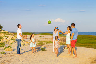 People playing on beach against sky