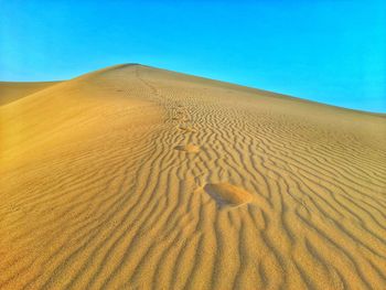 Sand dunes in desert against clear blue sky