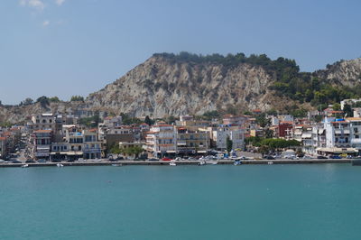 Sea by cityscape against clear sky