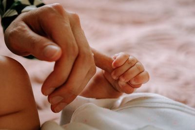 Close-up of baby hand holding mother's finger 