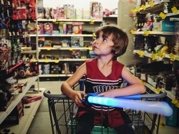 Boy sitting in shopping cart at toy shop