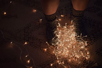 Low section of woman with illuminated christmas lights