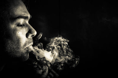 Man smoking cigarette against black background